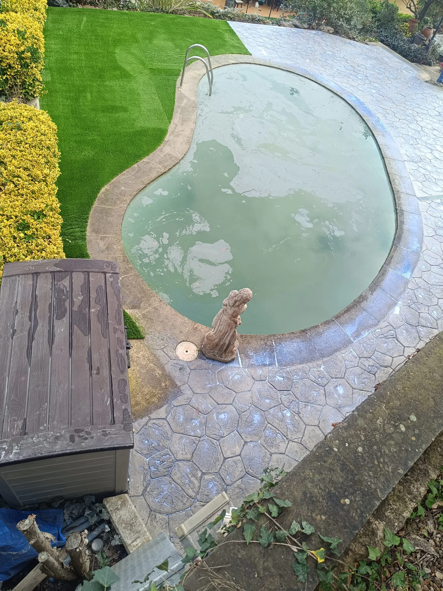 Césped artificial en zona de piscina con corona de hormigón impreso
